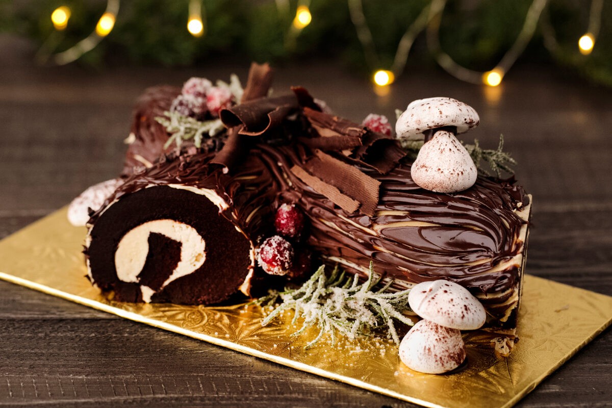 Buche de Noel sliced on a table surrounded by lights