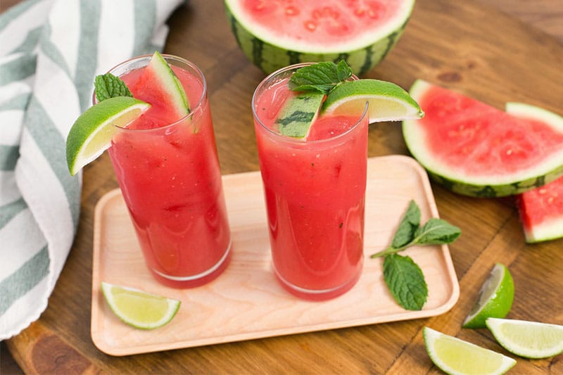 Two glasses of Watermelon Agua Fresca with watermelon wedges off to the side