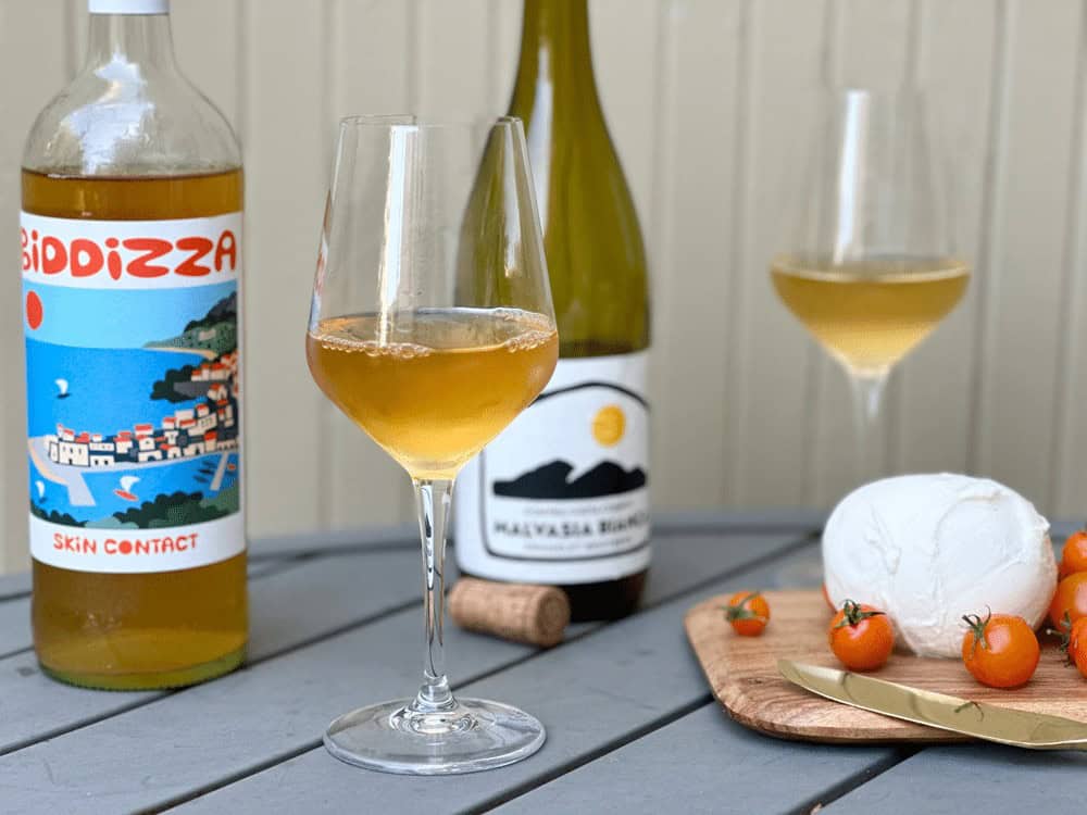 A Bottle Of Biddiza And Malvasia Next To Each Other On A Picnic Table Uncorked Next Tto Mozzarella And Cherry Tomatoes