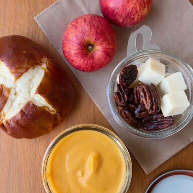 Bowl Of Curry Soup Shot From Above With Pretzel Bun Apples Walnuts And Cheese