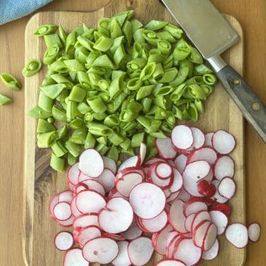 Cut Up Onions And Radishes Shot From Above On Cutting Board With Blue Napkin