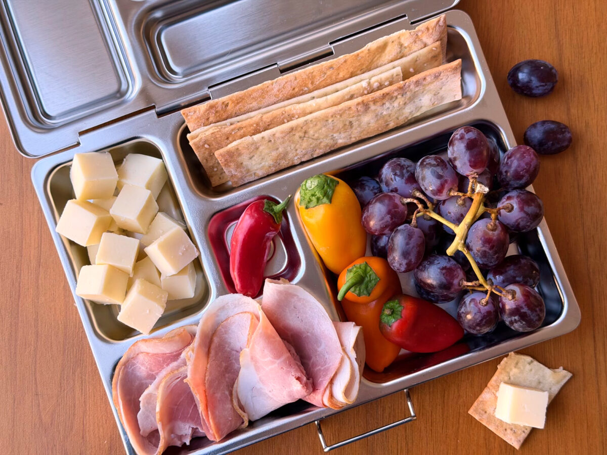 Open Lunch Box Of Cheese Peppers Meats Grapes And Crackers