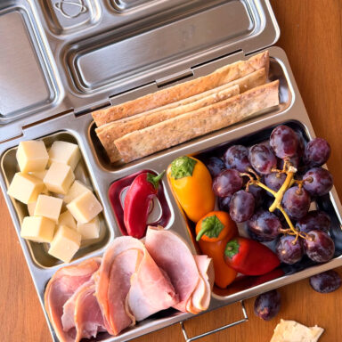 Open Lunch Box Of Cheese Peppers Meats Grapes And Crackers One Cracker Out Of Box