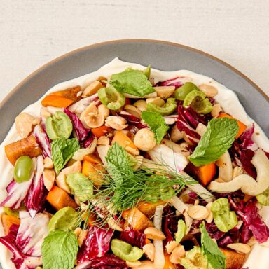 Plated Autumn Salad With Persimmons Fresh Herbs Greens And Labneh